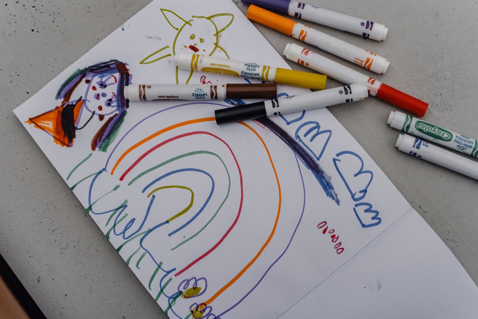From above of colorful drawing on white sheet of paper in drawing book with color markers