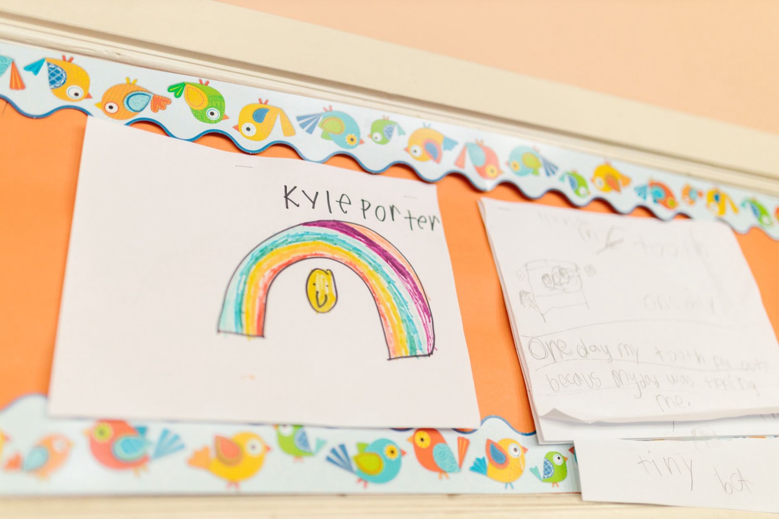 Vibrant children's drawings hang on a decorated classroom wall.