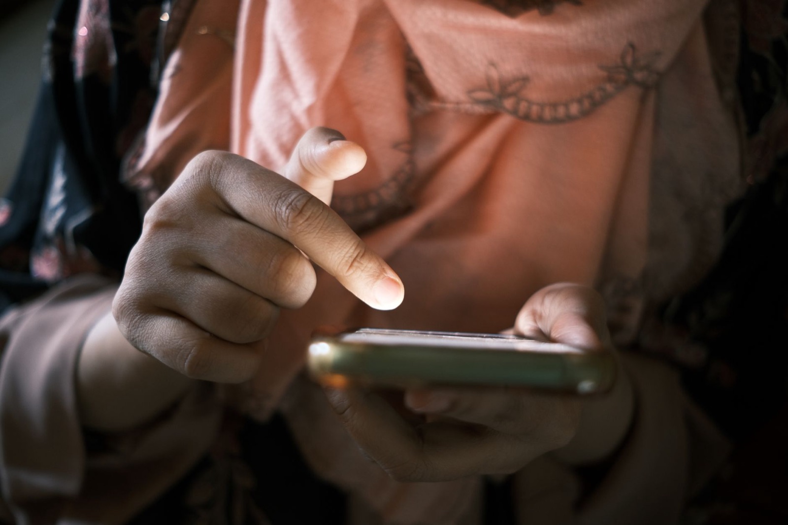 Nahaufnahme von Händen, die drinnen ein Smartphone bedienen, und zeigt die Touch-Technik.