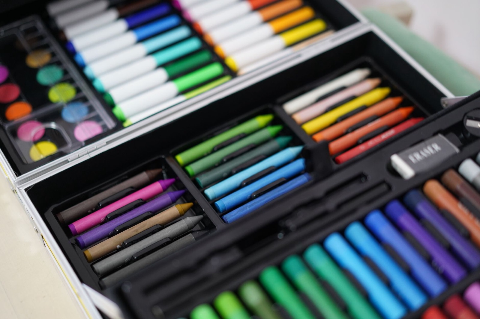 Colorful array of art materials including crayons and paints in an open art kit box, ready for creative use.