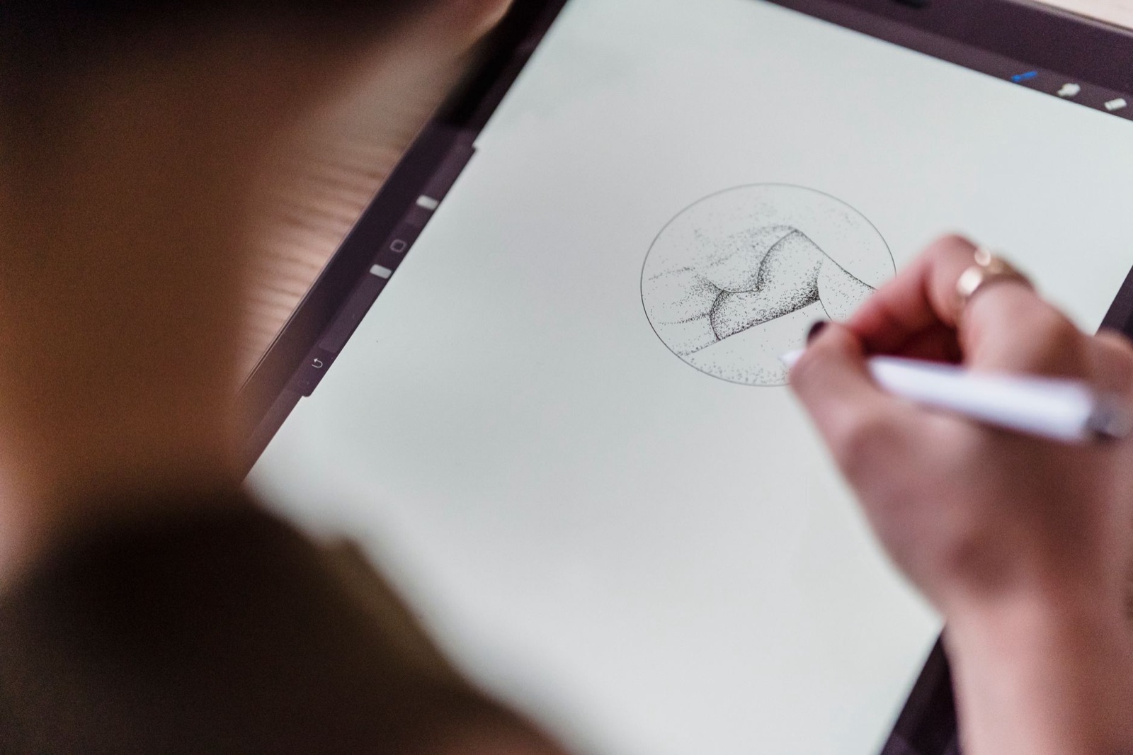 Aufsicht auf einen Künstler, dessen Gesicht nicht zu sehen ist: Mit einem Stift in der Hand zeichnet er auf einem Grafiktablett eine kreative Skizze.