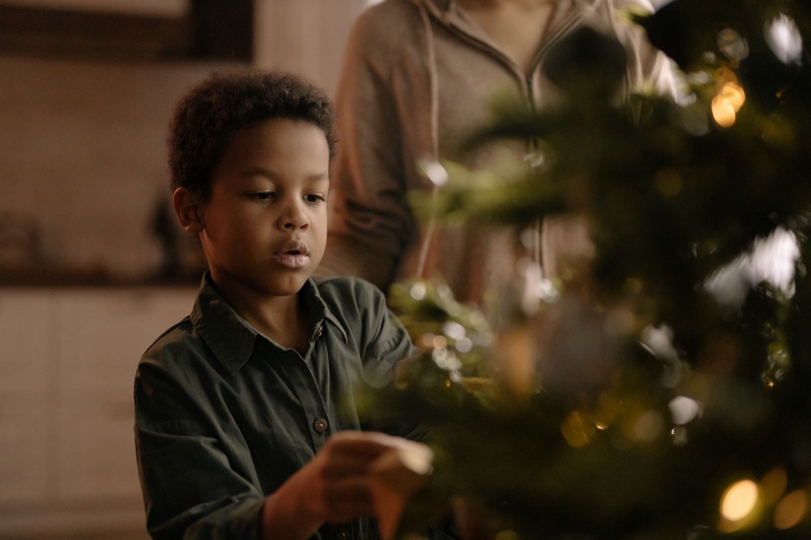 A young boy decorating the Christmas tree during the holiday season indoors.