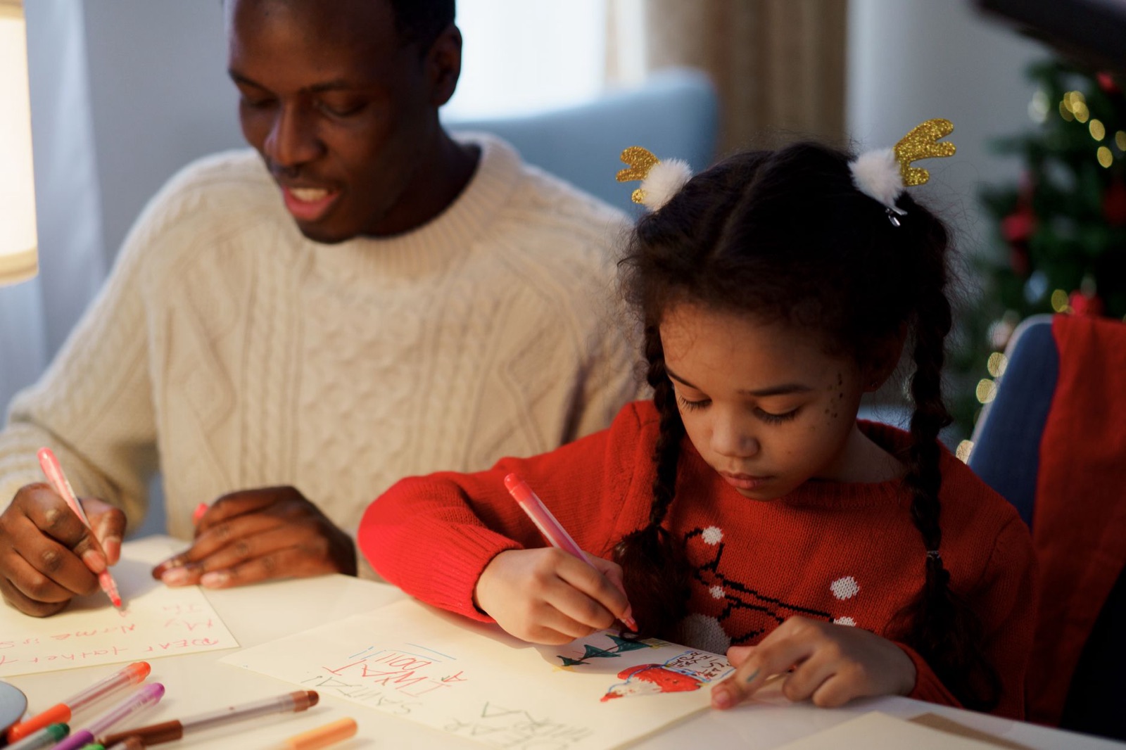 Father and daughter enjoying a creative moment, making Christmas cards together.