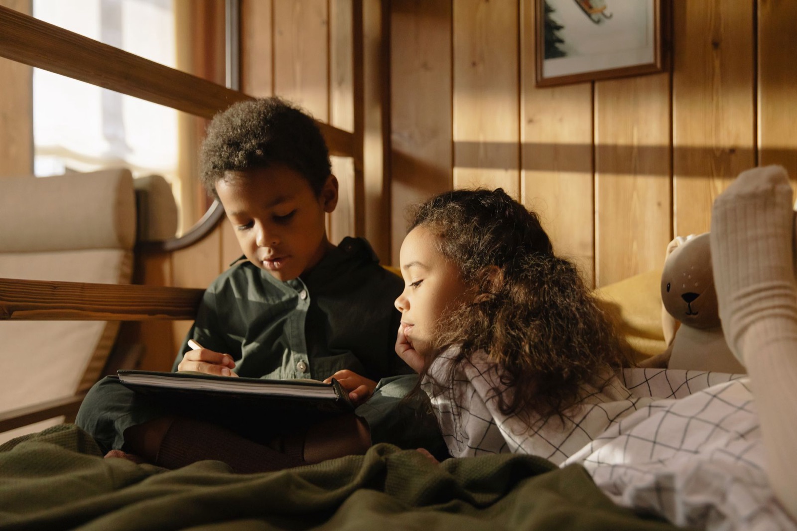 Two children enjoying a reading session together in a warm and cozy room.