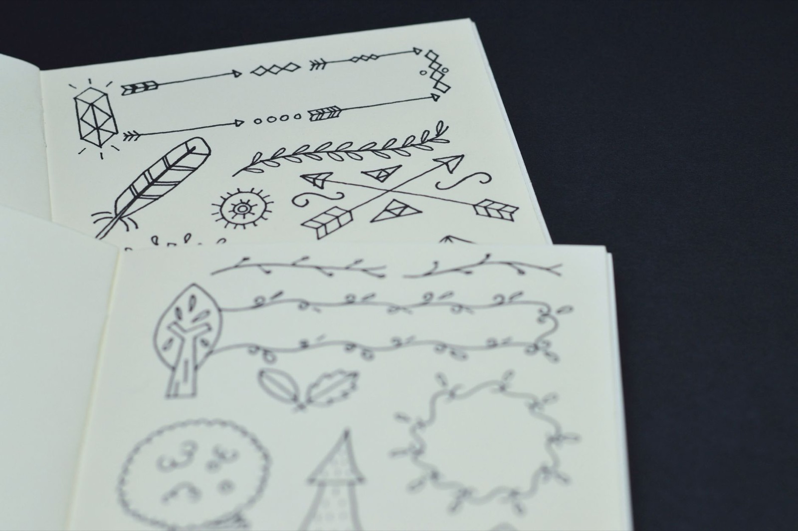 Artistic black doodles on white paper, featuring arrows and nature elements.