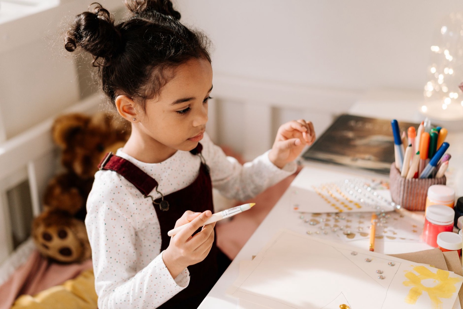 A young girl enjoying a creative arts and crafts session indoors with paints and markers.