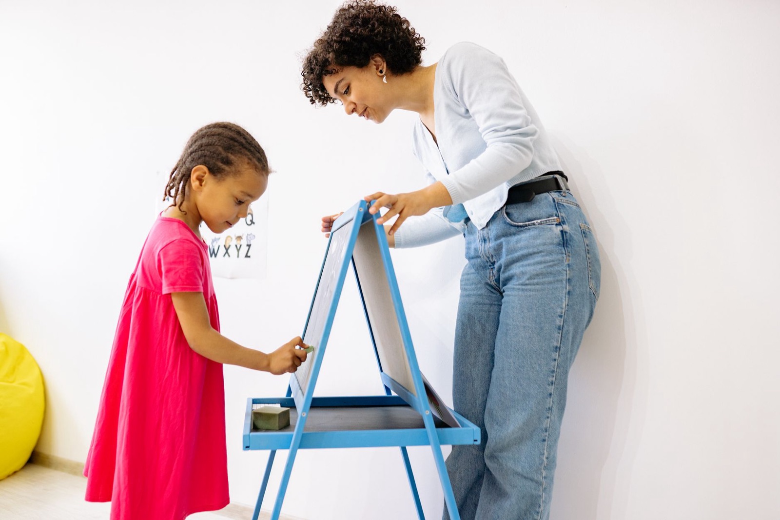 A child and teacher interact at a chalkboard, fostering education and creativity.