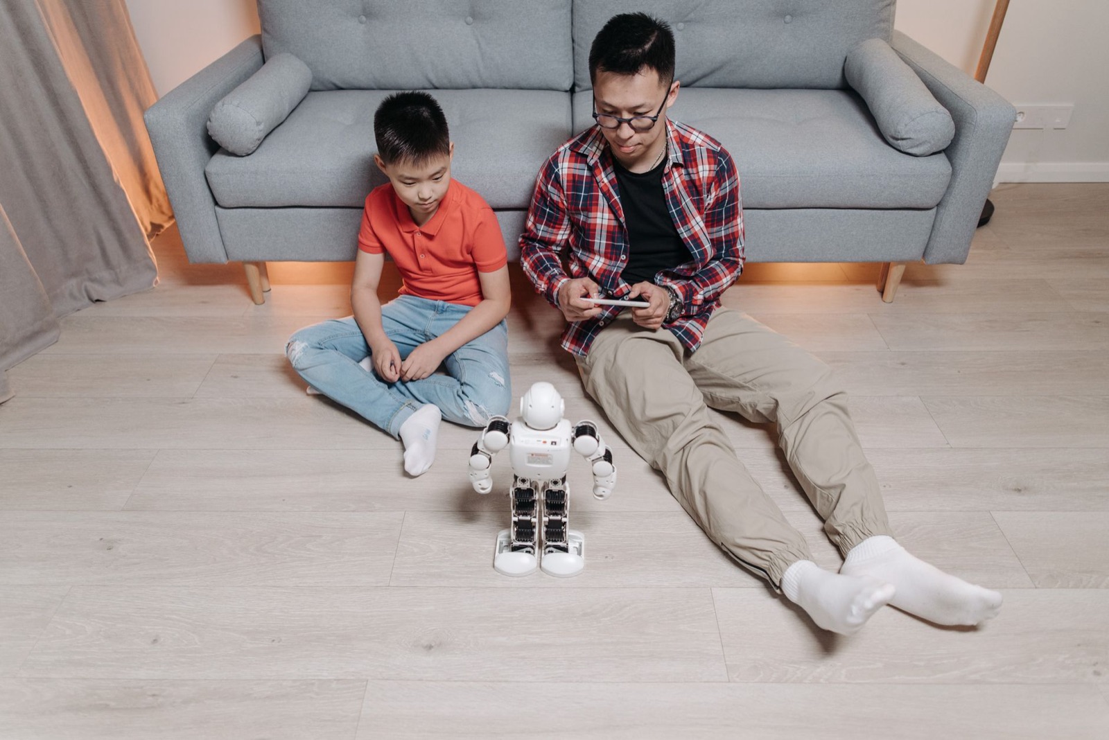 Vater und Sohn beschäftigen sich zu Hause gemeinsam mit Robotik und Technik und spielen mit einem Roboter.