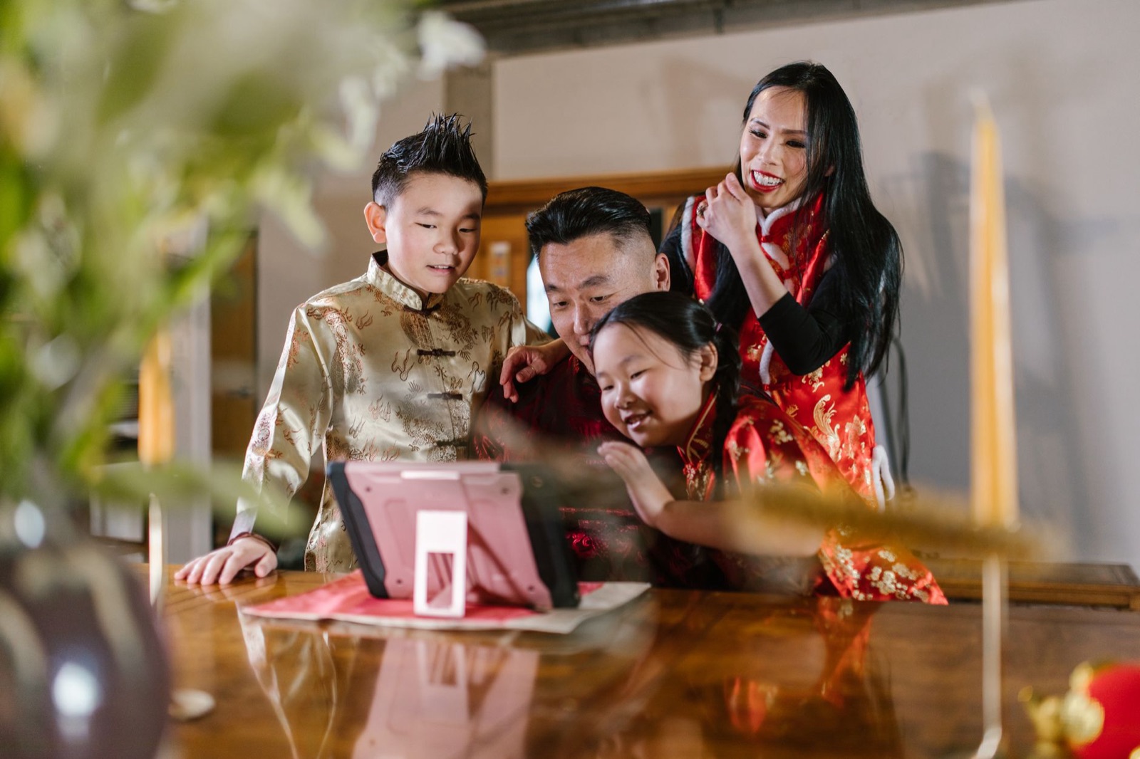 A family dressed in traditional clothing enjoys a video call together, showcasing technology and cultural connection.