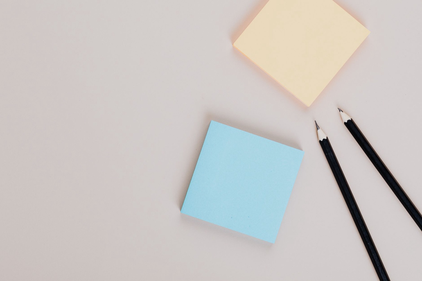 Top view of colorful sticky notes and sharp pencils on a neutral surface, minimalism style.