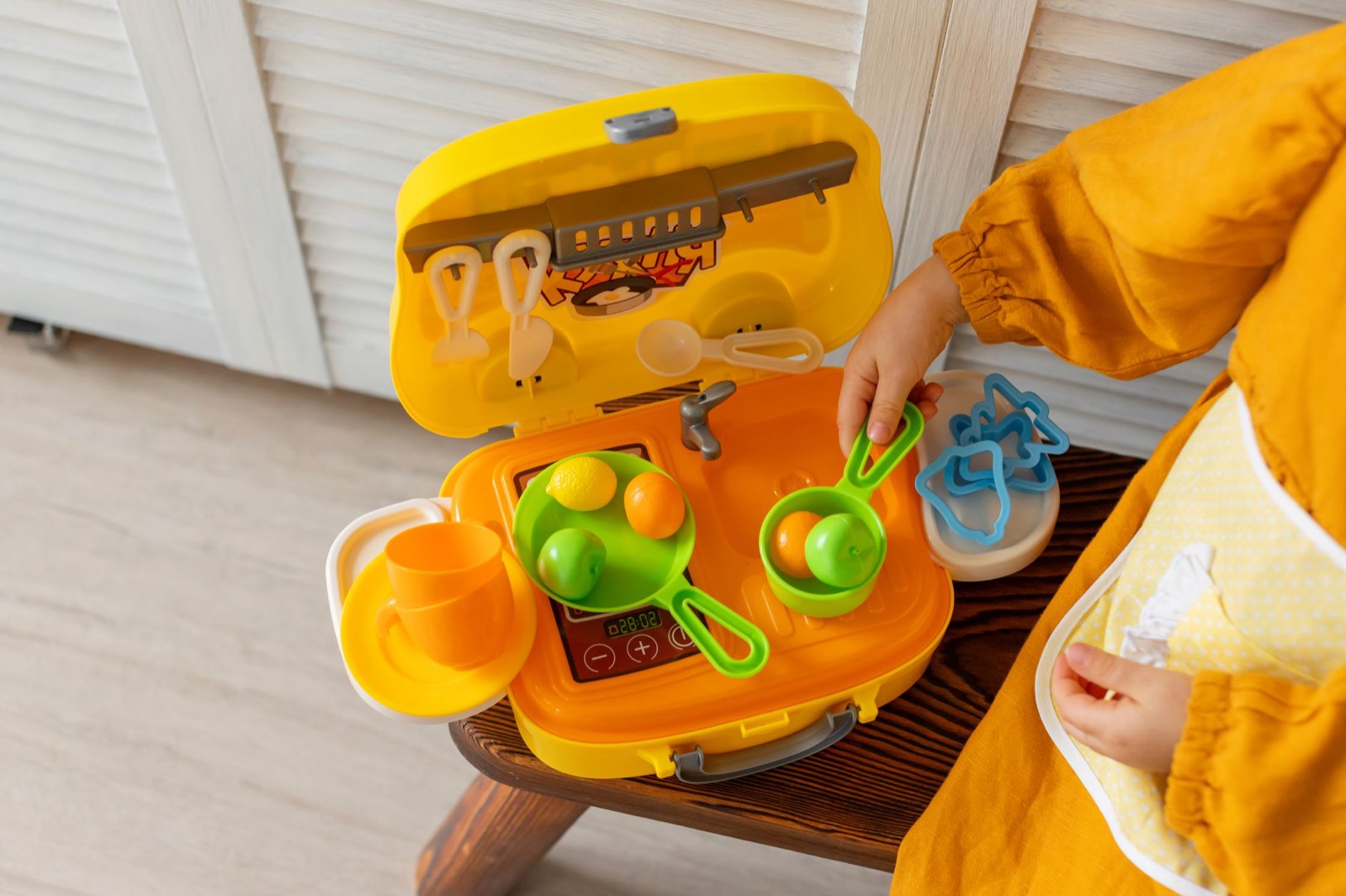 A child playing with a toy kitchen set, engaging in creative pretend play indoors.