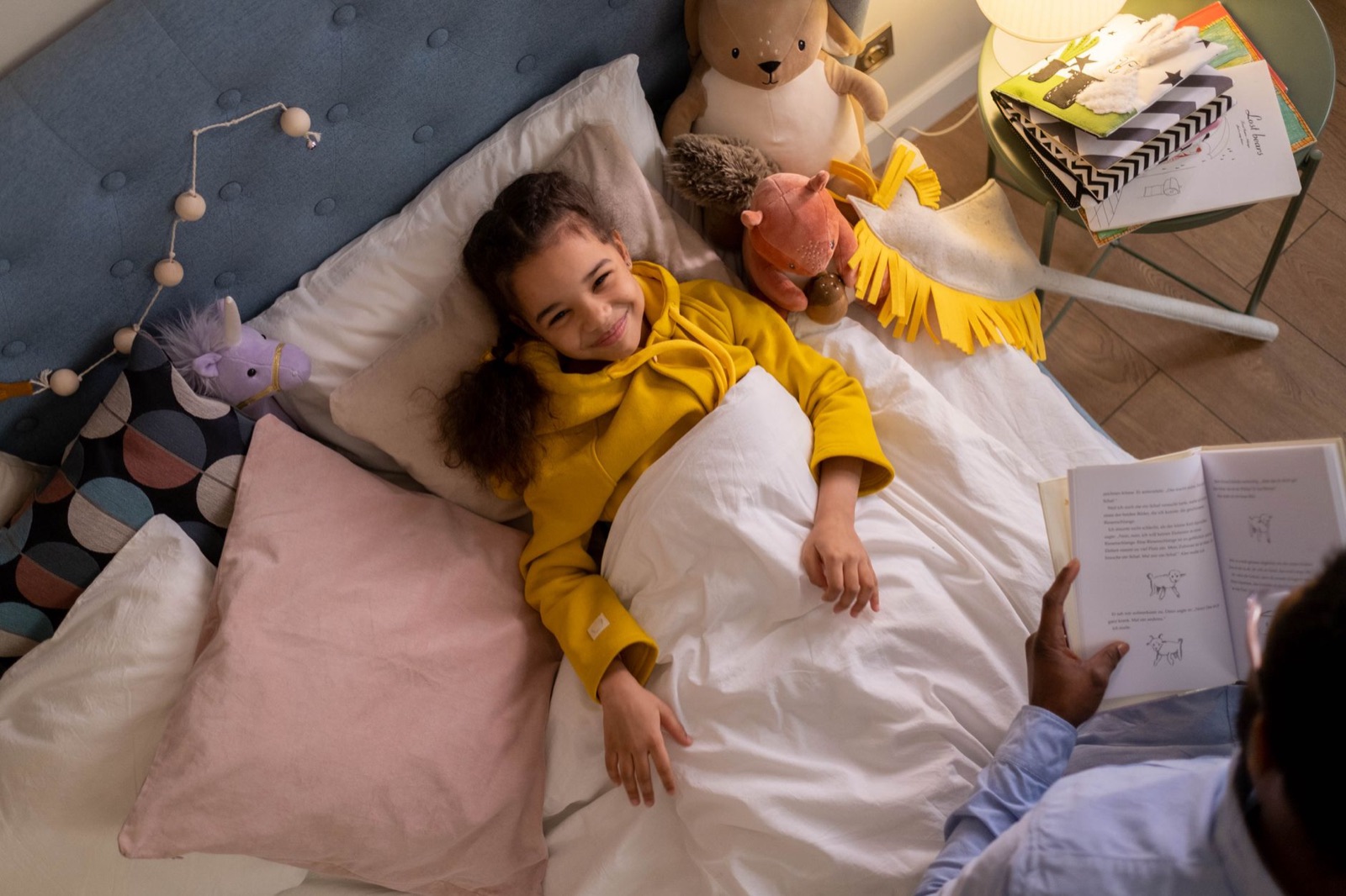 A happy child enjoys a bedtime story in a cozy, toy-filled room.