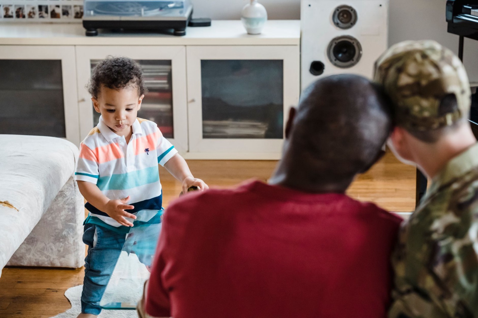 A family gathering with a child playing while parents watch lovingly in a cozy home setting.