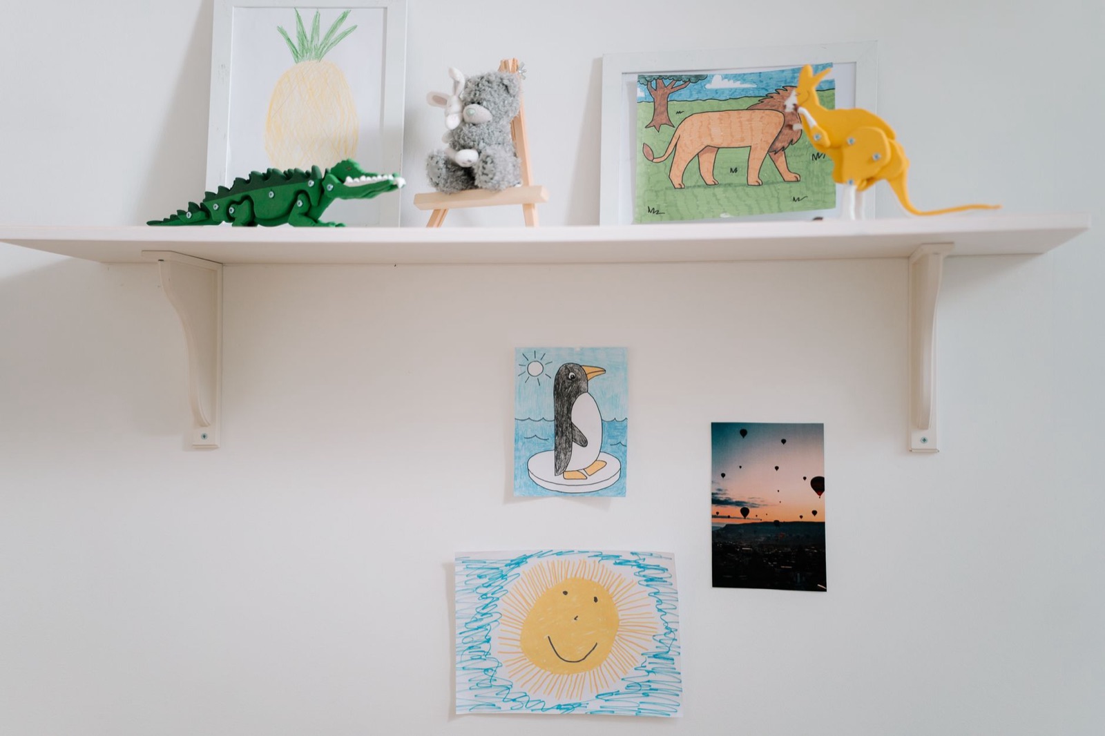 A cozy display of children's artwork and toys on a wall-mounted shelf, capturing creativity and imagination.